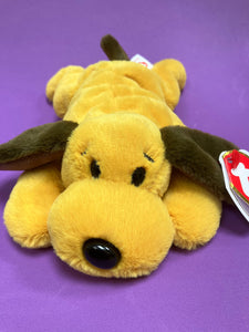 Beanie baby dog lying flat towards camera